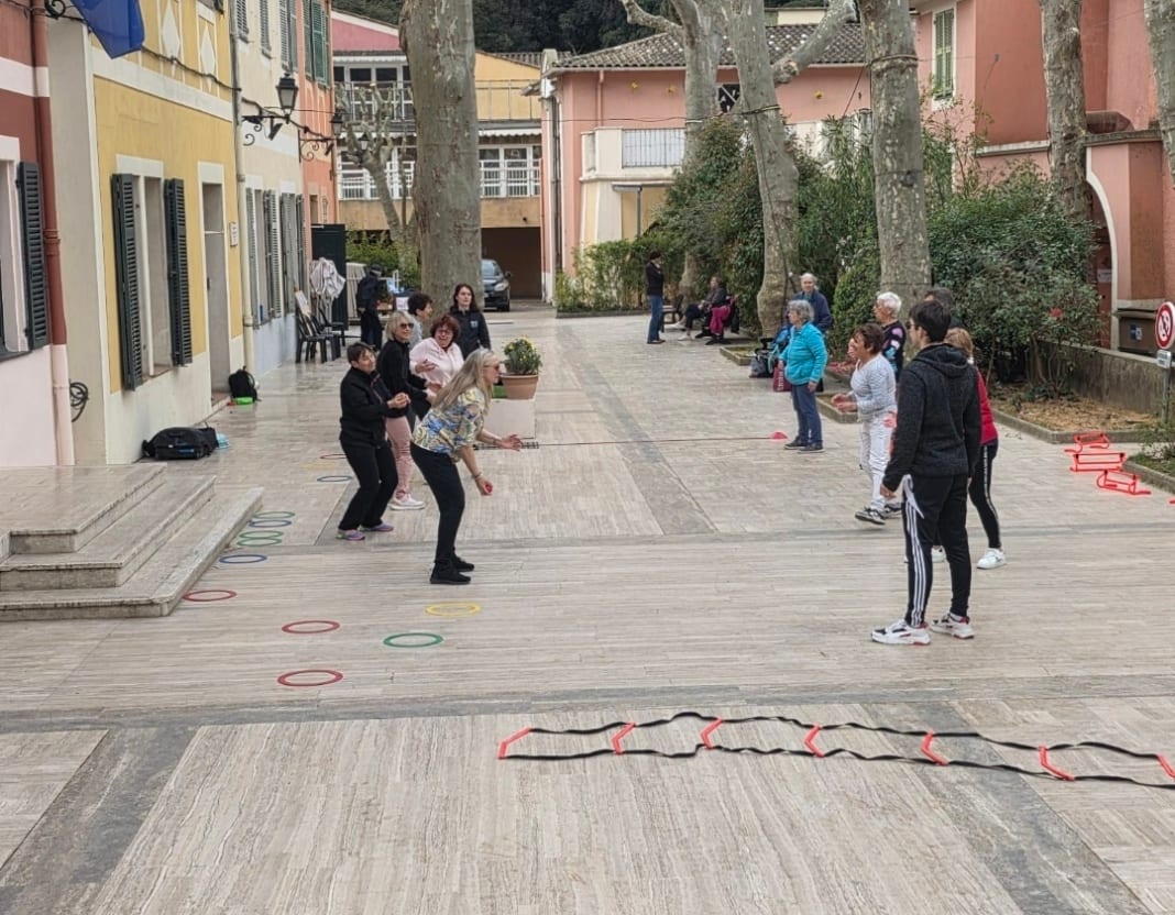 Séance d’activité physique en plein air dans les Alpes-Maritimes : un groupe de participants suit les exercices d’une animatrice, avec des cerceaux et une échelle de motricité posés au sol.